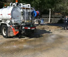 A water truck sprays water on permeable pavers at Oak Park